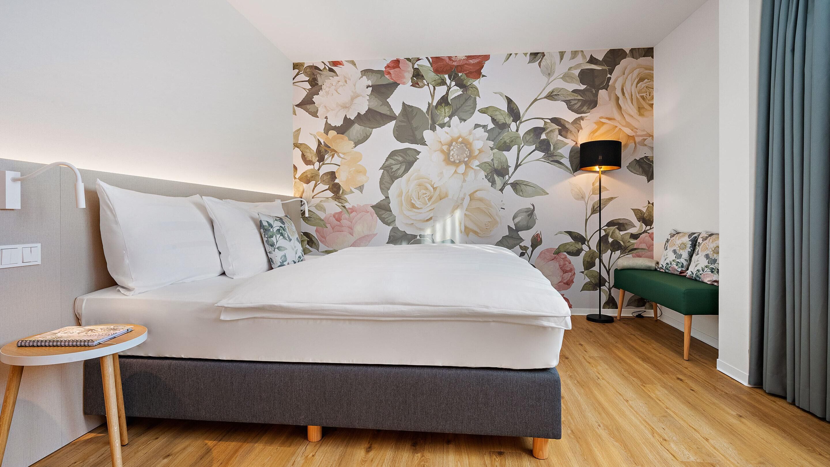 Een slaapkamer met een bed, nachtkastje, lamp en een groene bank.