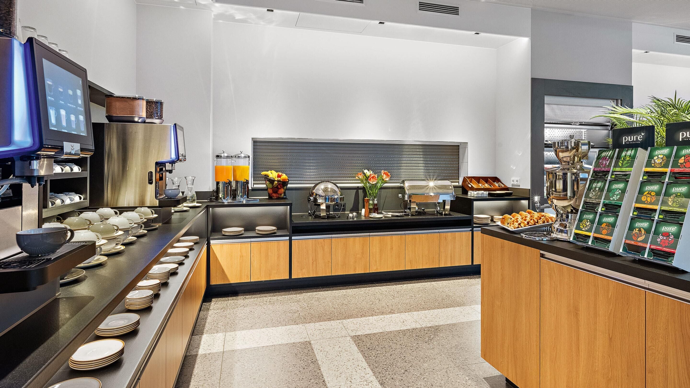 A modern kitchen with a coffee station, tea selection, and a fruit bowl.