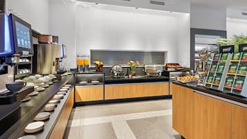A modern kitchen with a coffee station, tea selection, and a fruit bowl.