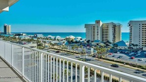 A coastal hotel with multiple high-rise buildings, a parking lot, and a clear view of the ocean.