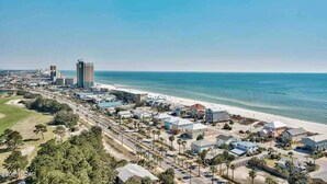 A coastal town with a beach, residential buildings, and a tall hotel.
