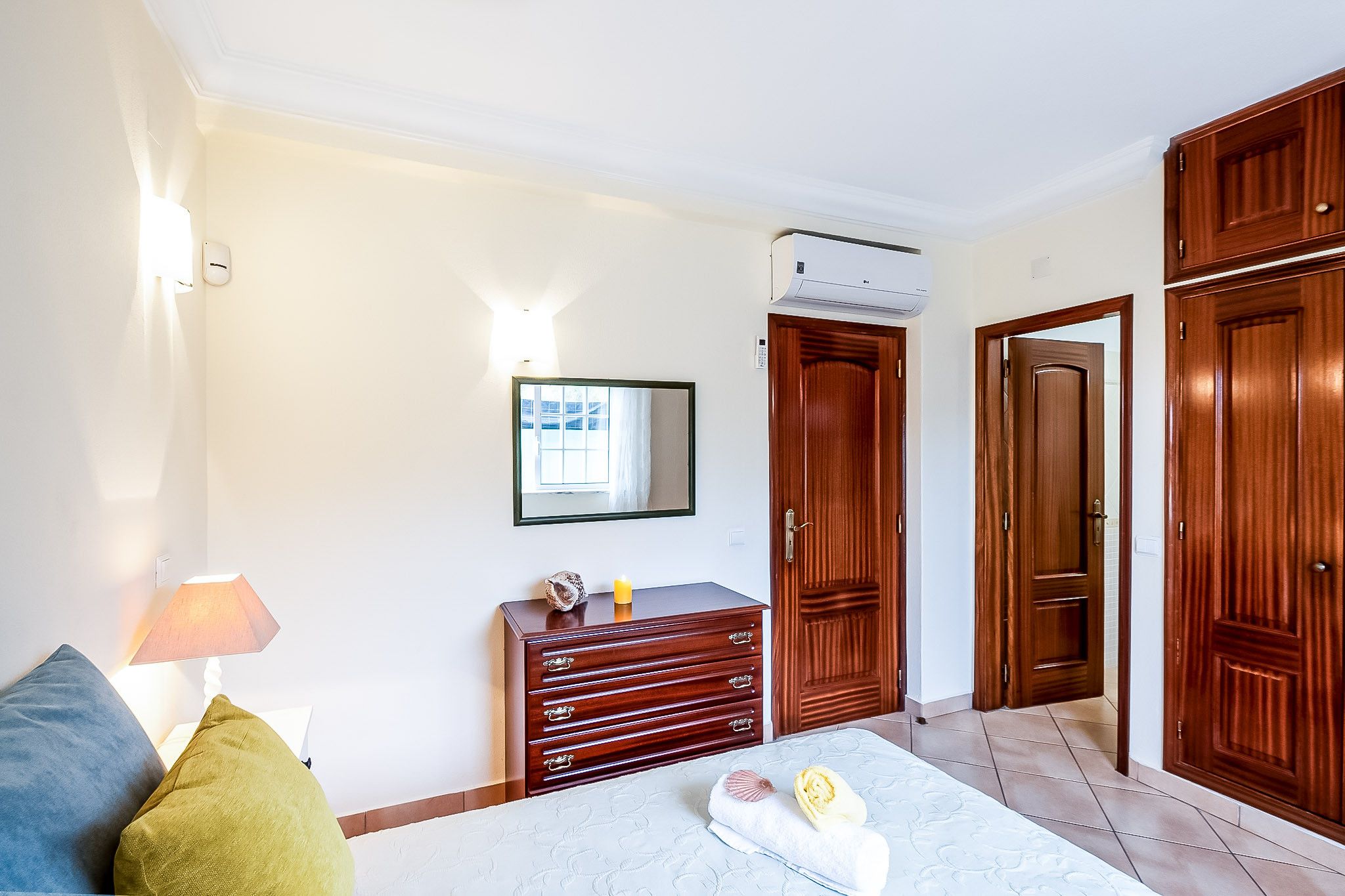 A bedroom with a bed, dresser, wardrobe, and a mirror.