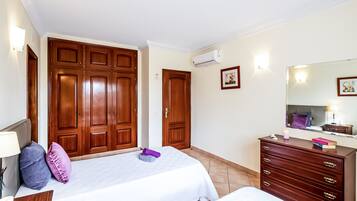 A hotel room with two beds, a dresser, a mirror, and a wardrobe.