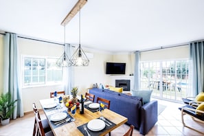 A modern living room with a dining area, a sofa set, and a TV mounted on the wall. - Getaway w/ heatable pool and jacuzzi in Albufeira (Albufeira)