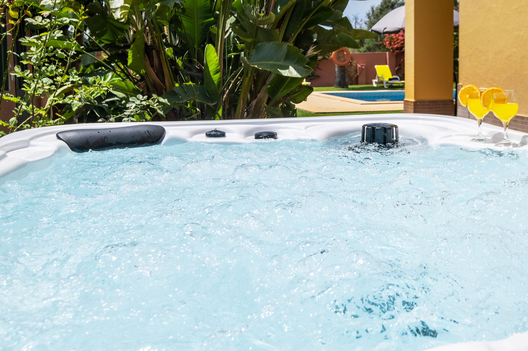 Un jacuzzi con chorros de agua, rodeado de follaje y una zona de piscina.