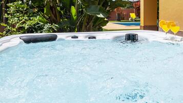 Un jacuzzi con chorros de agua, rodeado de follaje y una zona de piscina.