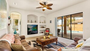 A living room with a ceiling fan, a flat-screen TV, a coffee table, and a sofa. - Bahama Sunset 5 Bedrooms (Davenport)