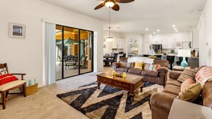 A spacious living room with a brown leather sofa, a wooden coffee table, and a ceiling fan. - Bahama Sunset 5 Bedrooms (Davenport)