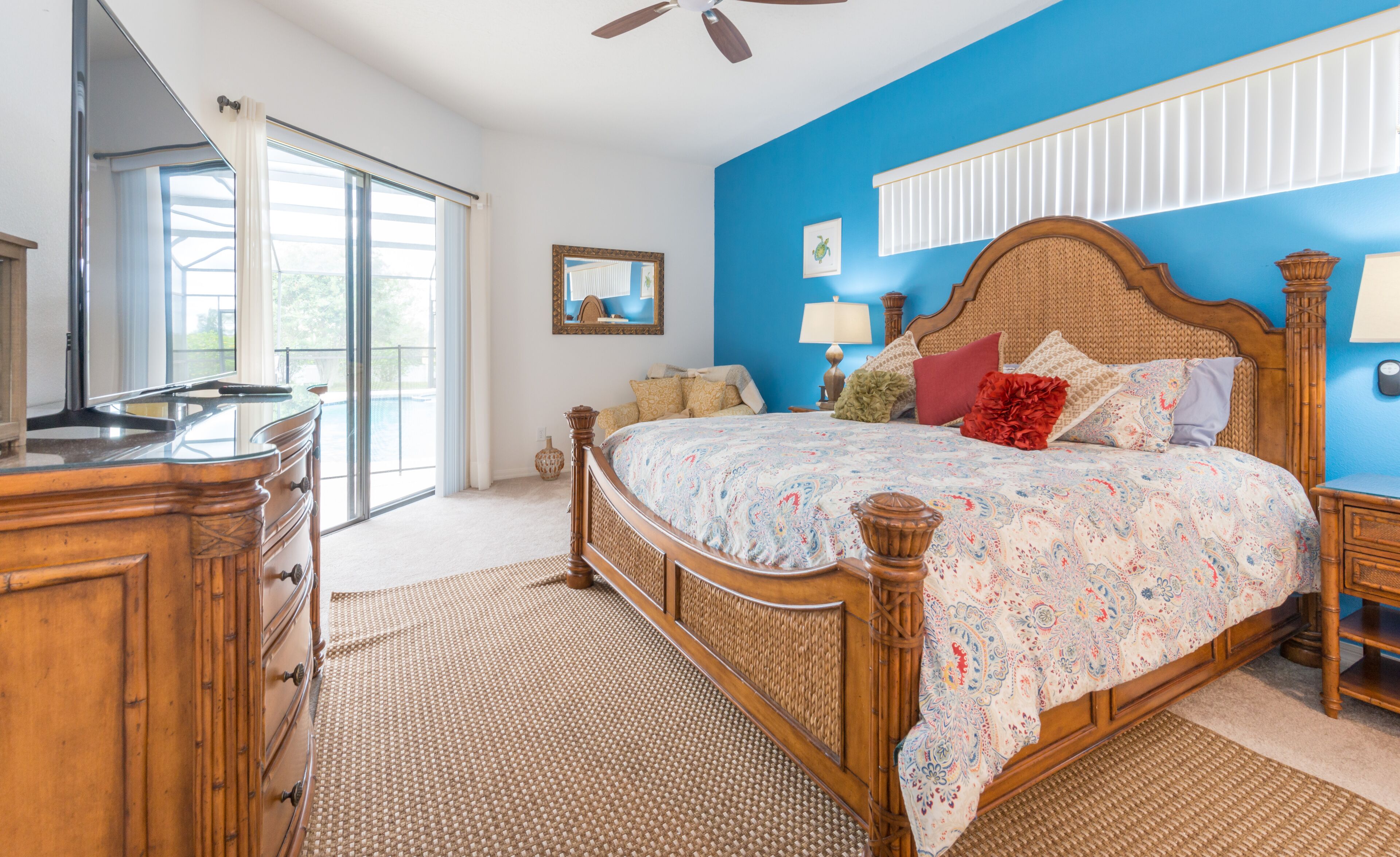 A bedroom with a large bed, wooden dresser, and a ceiling fan.