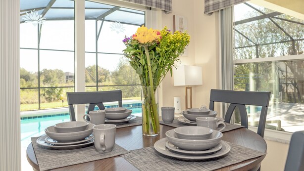 A dining table set with plates, bowls, and cups, with a vase of flowers in the center. - Balmoral Breeze 5 Bedrooms (Davenport)
