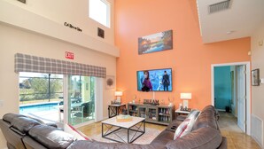 A spacious living area with a leather sofa, a coffee table, and a flat-screen TV mounted on the wall. - Balmoral Breeze 5 Bedrooms (Davenport)