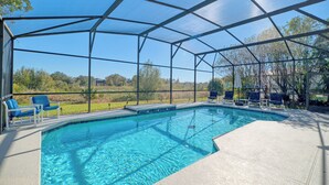 An indoor swimming pool with clear blue water, surrounded by a covered area with chairs and a view of the outdoors. - Balmoral Breeze 5 Bedrooms (Davenport)