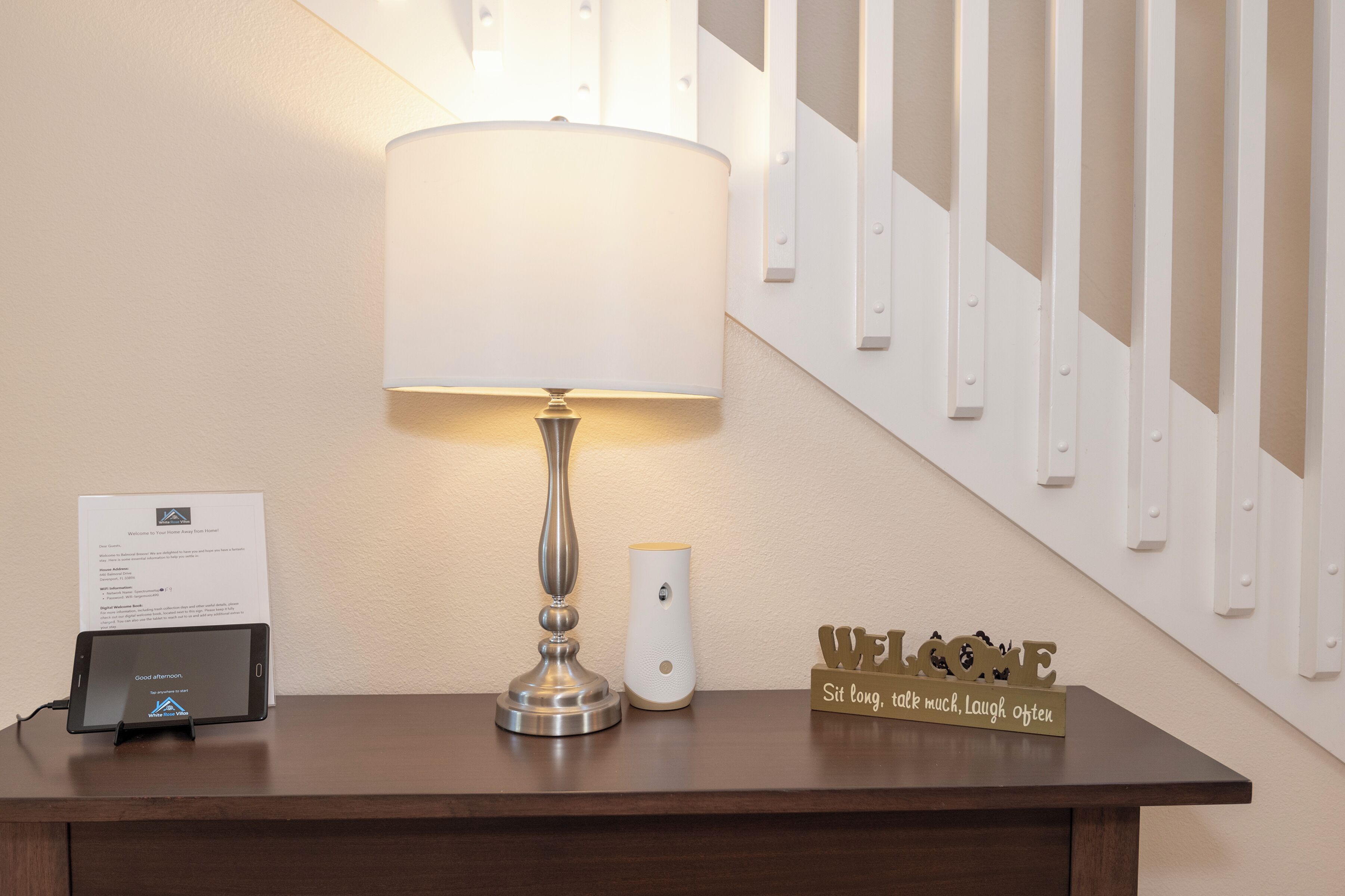 A reception desk with a lamp, a sign, and a tablet displaying 'Good afternoon'.