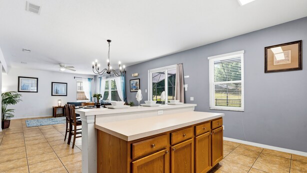 A kitchen with a central island, wooden cabinets, and a dining area with chairs and a table.