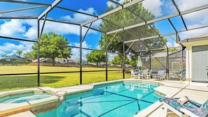 A covered outdoor swimming pool with lounge chairs and a view of the surrounding neighborhood.