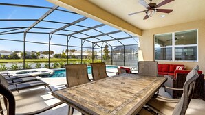 Une terrasse couverte avec une piscine, des sièges d’extérieur et une table.