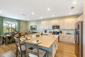 Una cocina moderna con armarios blancos, electrodomésticos de acero inoxidable y una isla grande con asientos.