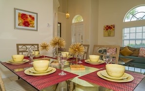 Enjoy meals in this beautifully set dining area with a long table, decorative centerpiece, and elegant glassware.