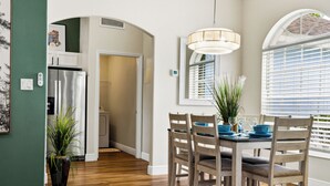 A dining area with wooden chairs, a table, and a hanging light fixture. - Sapphire Sky Villa 4 Bedrooms (Clermont)