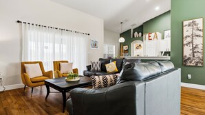 A modern living room with a sofa, armchairs, a coffee table, and a kitchen area in the background. - Sapphire Sky Villa 4 Bedrooms (Clermont)