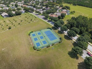 An aerial view of a residential area with houses, a tennis court, and a road. - Sapphire Sky Villa 4 Bedrooms (Clermont)