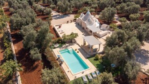 An aerial view of a property with a swimming pool, a gazebo, and olive trees.