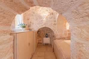 A stone-walled room with a small table and a cabinet.