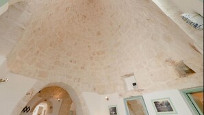 A high ceiling with exposed stonework, a framed picture, and a small window. - Trullo Paleo (Ceglie Messapica)