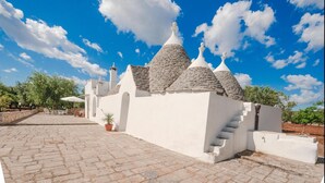 A white building with conical roofs and a paved courtyard. - Trullo Paleo (Ceglie Messapica)