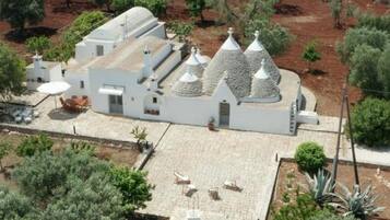 The building features a flat roof and conical structures, surrounded by a paved area with small trees and shrubs.