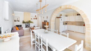 Un vaste espace de vie comprenant une table à manger blanche, des chaises blanches et une cheminée chaleureuse.