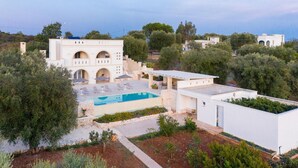Une villa blanche avec une piscine, entourée d’oliviers et offrant une vue sur la mer.