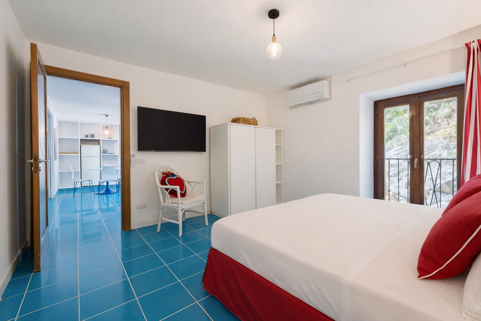 Un dormitorio con cama, televisión, armario y silla.
