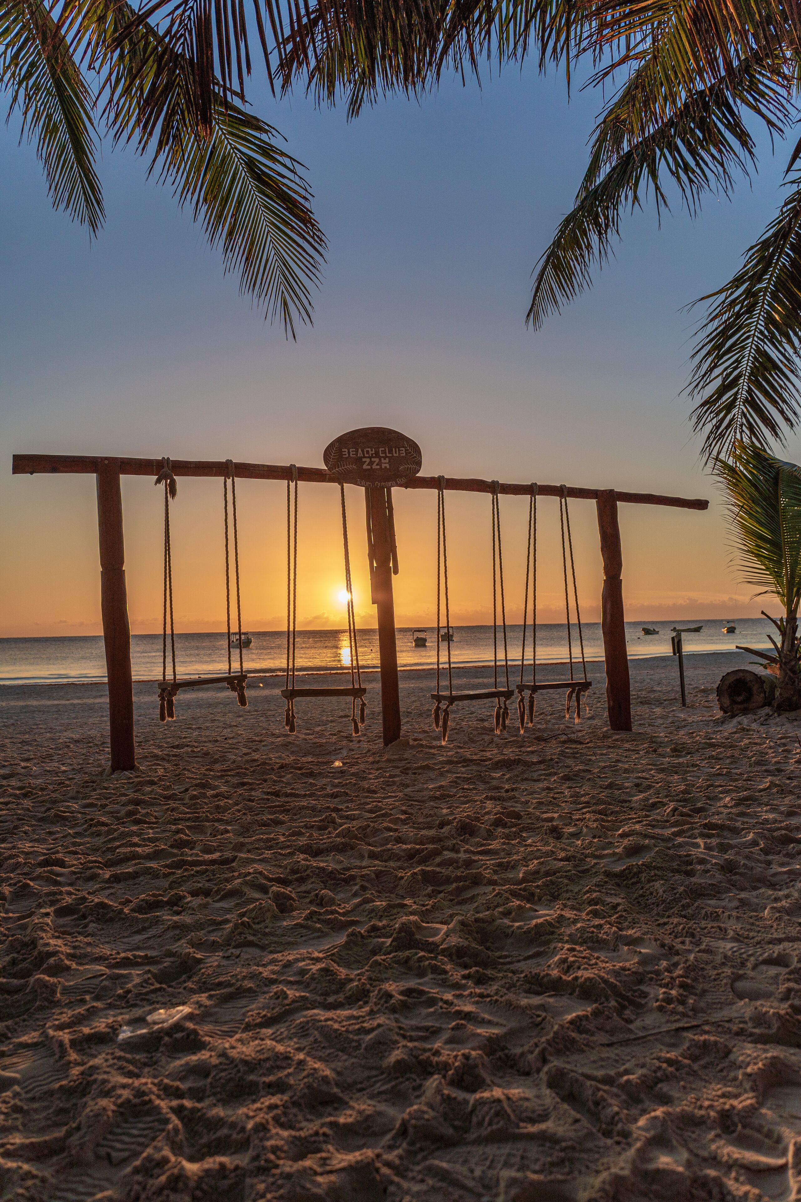 A beach swing set with a sign that reads "Beach Club 222".
