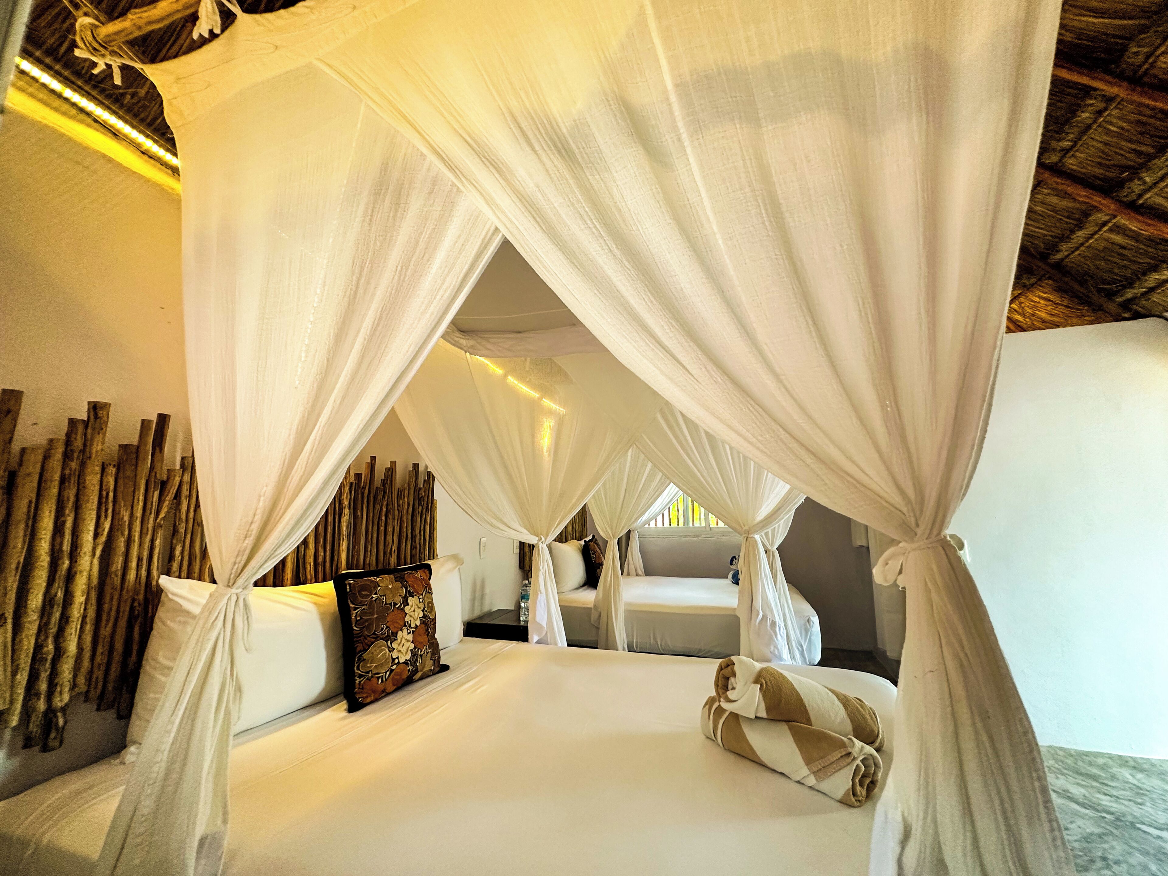 A room with a bed, white curtains, and a wooden wall.