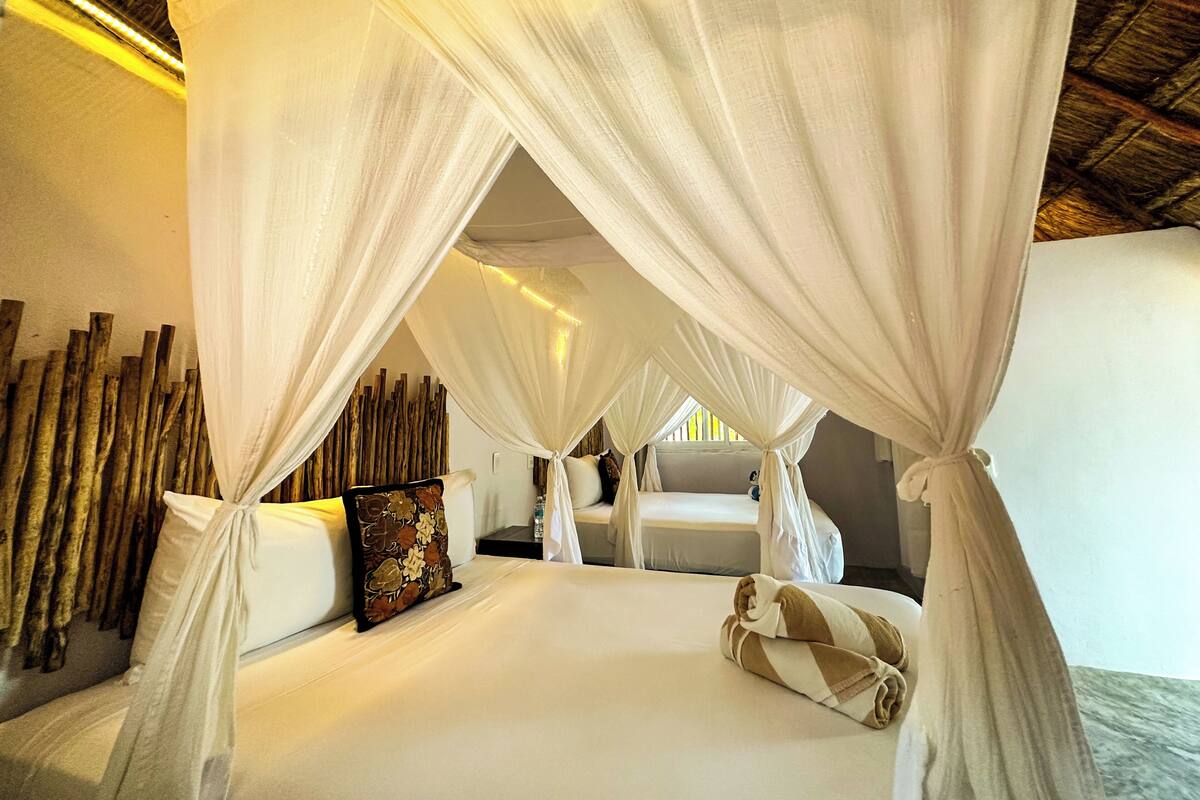 A room with a bed, white curtains, and a wooden wall.