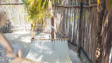 Una hamaca colgada entre bambúes en un entorno tropical con palmeras.