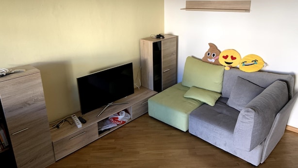 Un salon équipé d’un téléviseur à écran plat, de meubles en bois, d’un canapé gris et d’une petite table.