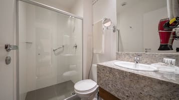 A modern bathroom with a glass shower enclosure, a white toilet, and a granite countertop with a sink.