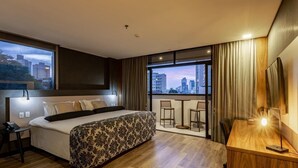 Una habitación de hotel moderna con una cama grande, un escritorio y un balcón con vistas a la ciudad.