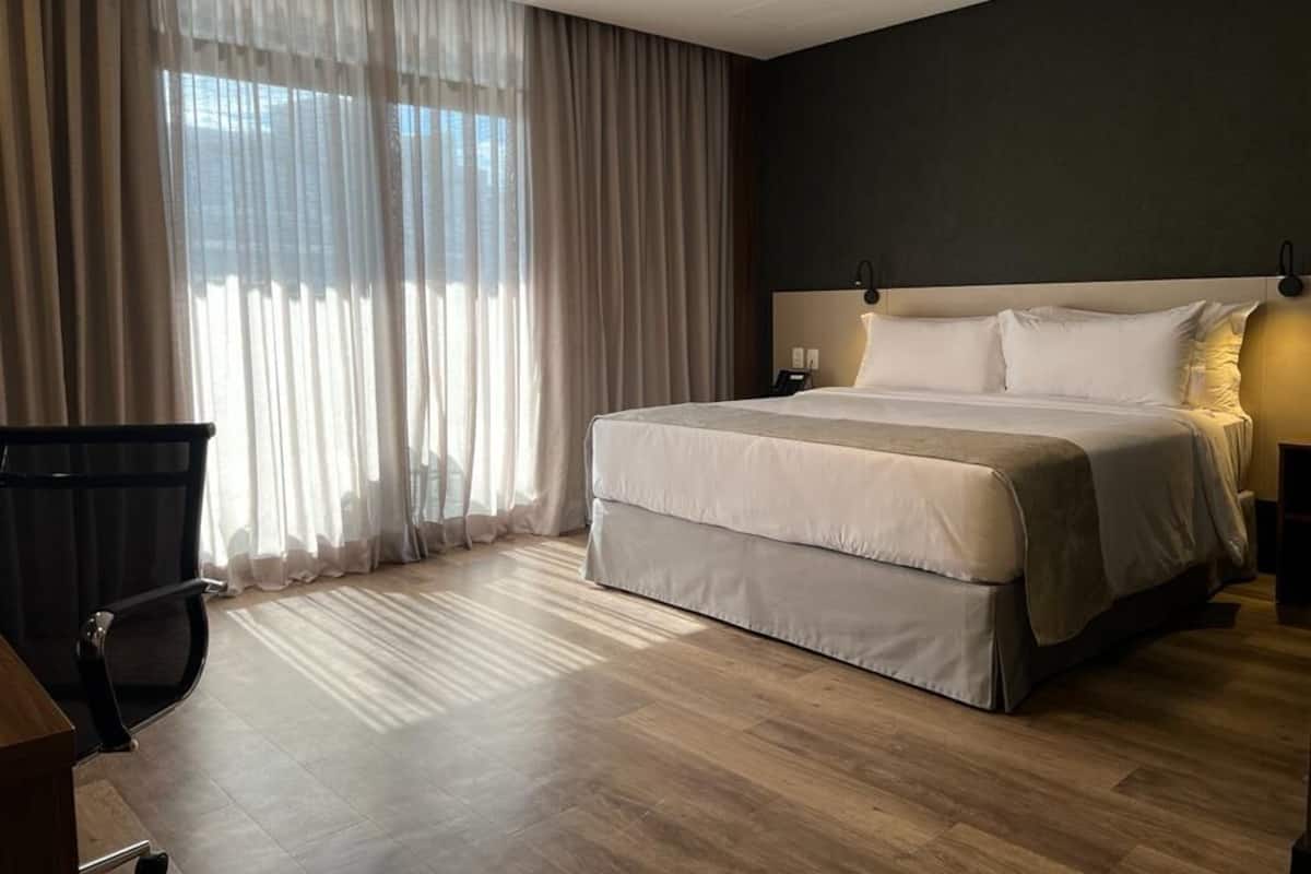 Quarto de hotel moderno com uma cama grande, uma escrivaninha e uma cadeira.