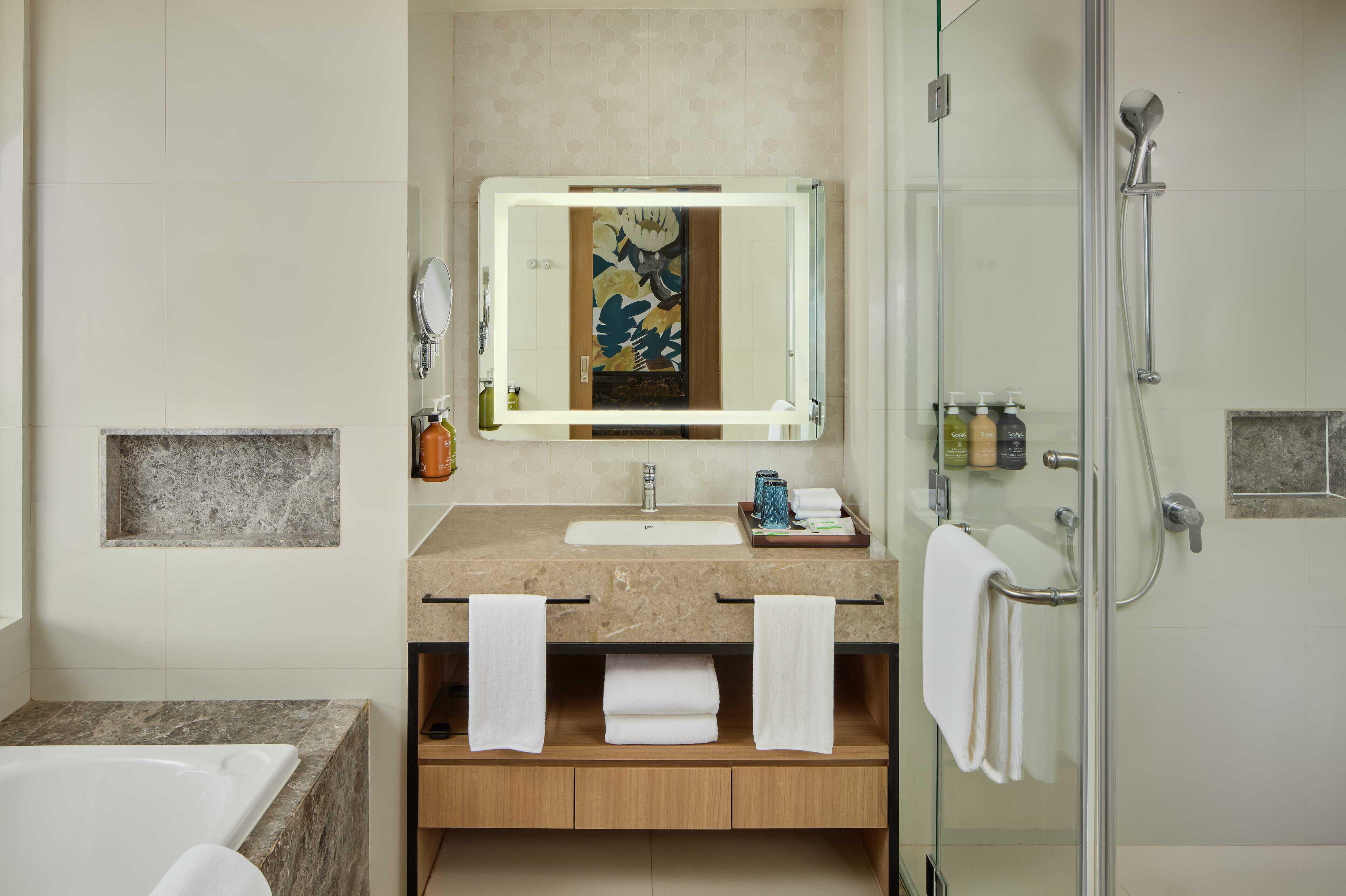 Un baño moderno con cabina de ducha de vidrio, lavamanos de mármol y un espejo grande.