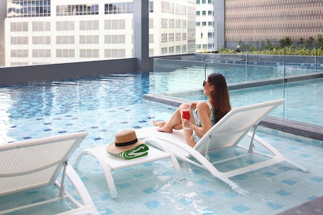 Una piscina al aire libre, sombrillas, sillones reclinables de piscina