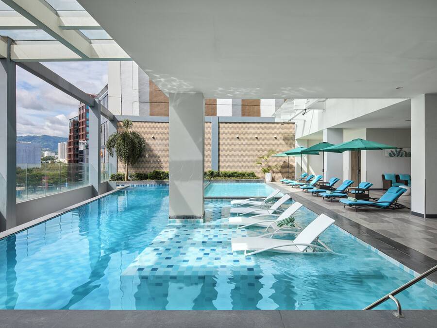 Una piscina al aire libre, sombrillas, sillones reclinables de piscina