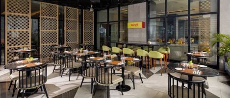 A restaurant with round tables and chairs, a modern ceiling design, and large windows.
