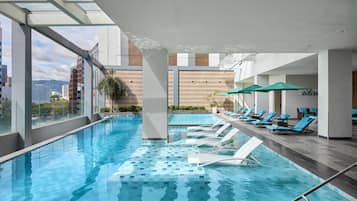 Een buitenzwembad, parasols bij het zwembad en ligstoelen