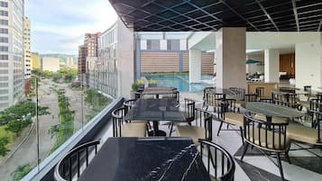 A balcony with a pool view, outdoor seating, and a view of the cityscape.