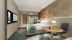 A modern hotel room with a bed, bedside table, chair, and a wall-mounted TV displaying the Holiday Inn logo. - Holiday Inn Cebu City by IHG (Cebu City)