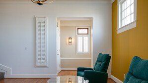 A room with a glass table, teal chairs, wooden flooring, and a yellow accent wall. - Mid-Century Modern Townhouse with High Views (Birmingham)