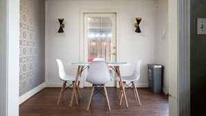 A dining area with a white table, four white chairs, and a modern chandelier. - Mid-Century Modern Townhouse with High Views (Birmingham)